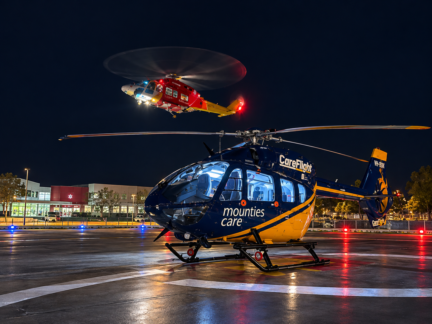 CareFlight helicopter on a lit helipad at night with a rescue helicopter overhead