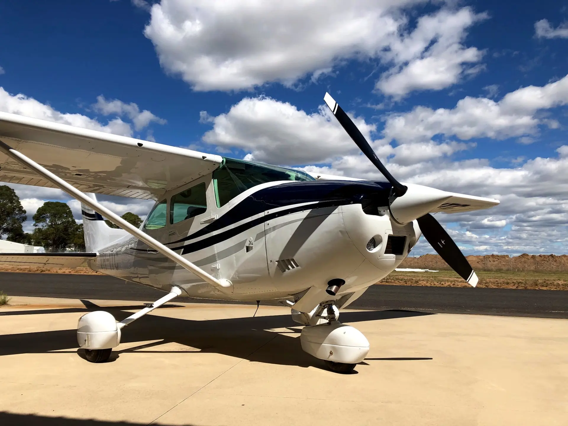 White and blue single-engine aircraft on a tarmac